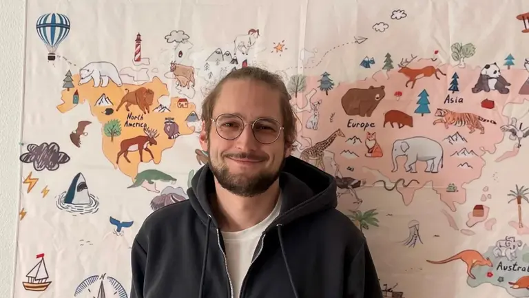 Junger Mann vor einem bunt bemalten Plakat