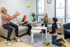 Kinder und Erzieherin spielen Ball