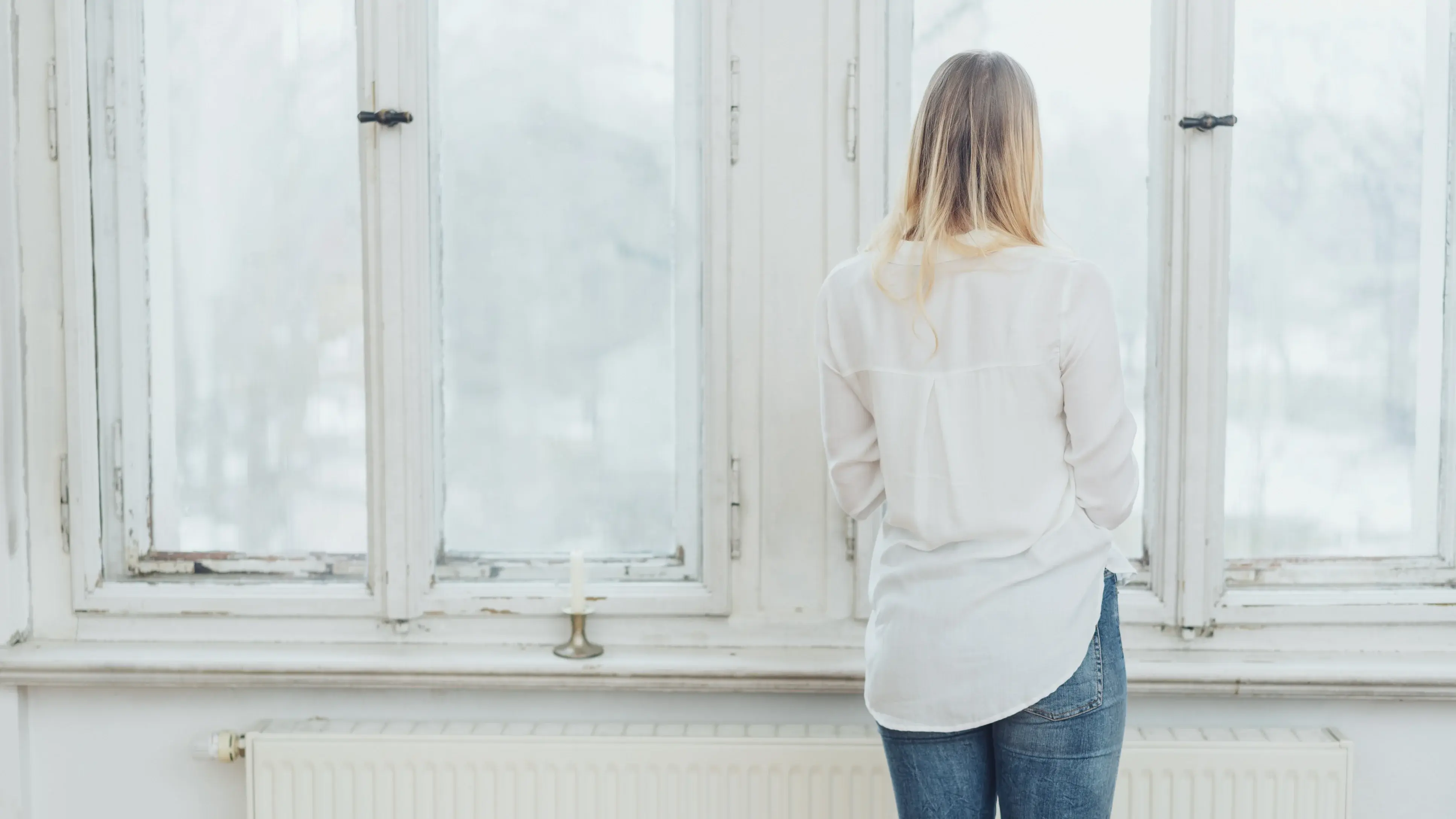 Frau steht niedergeschlagen am Fenster