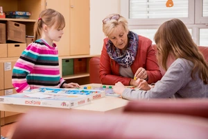 Zwei Kinder spielen mit Erzieherin ein Spiel 