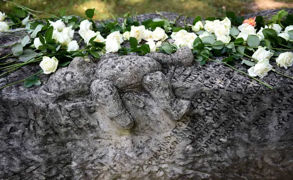 Das Foto zeigt den Gedenkstein von Vitos Rheingau mit weißen Rosen