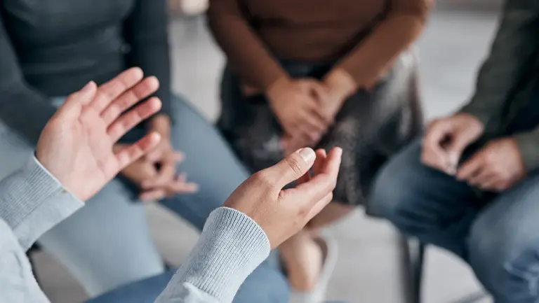 Gruppe von Menschen sitzt im Kreis und man sieht ihre Hände