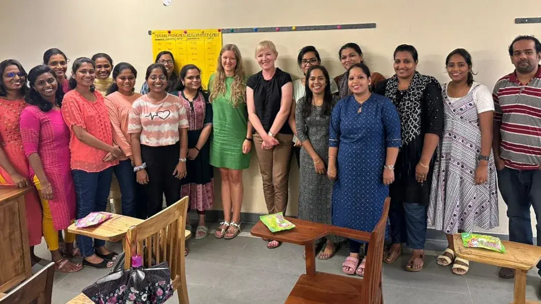 Eine Gruppe von Menschen steht in einem Klassenraum in Indien