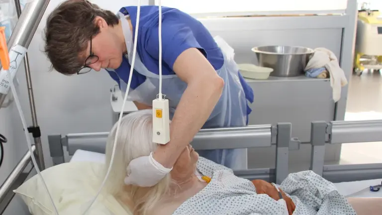 Beeindruckender Perspektivwechsel Pflegekraft beugt sich über eine Patientin im Krankenbett und hebt den Kopf vorsichtig an
